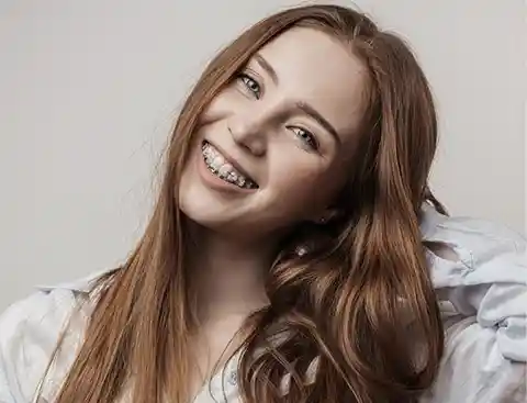 Redheaded girl with braces and a white shirt.
