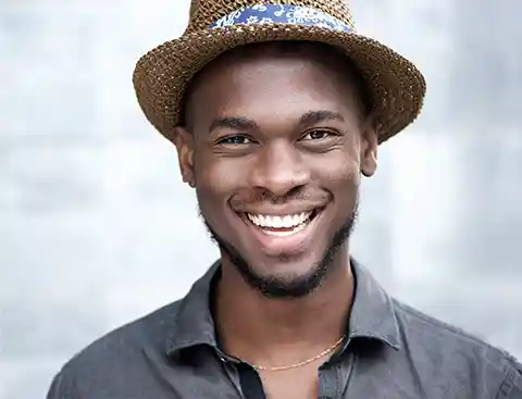 Smiling man with a straw fedora and black shirt.