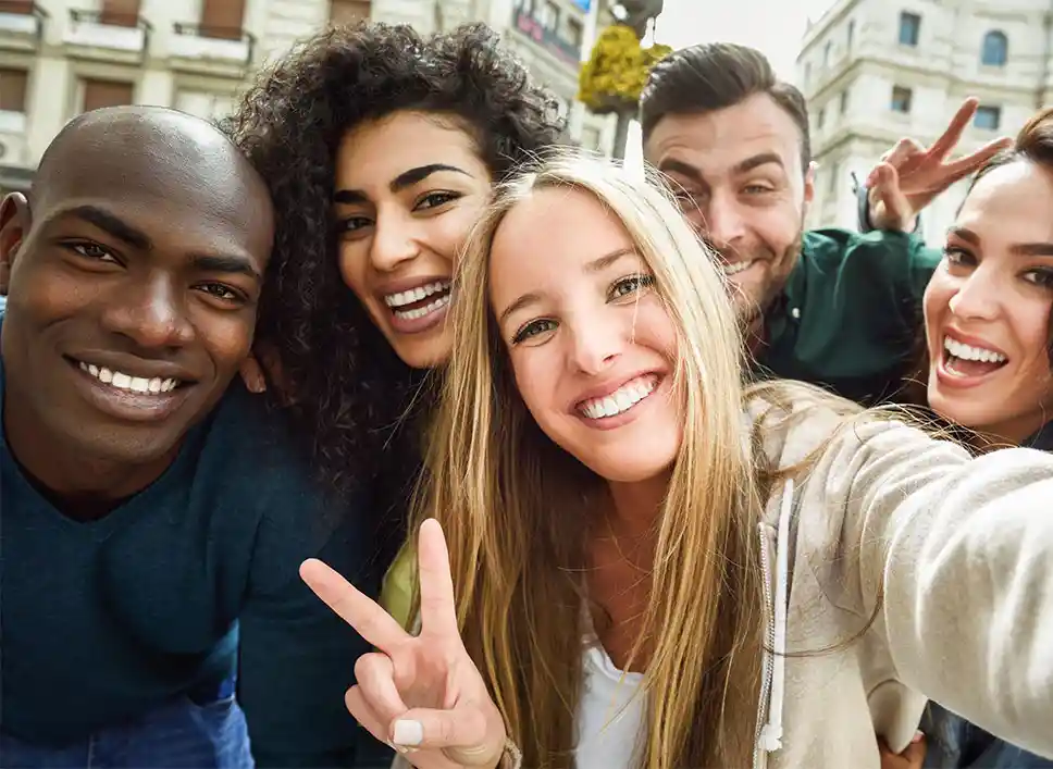 Five adults taking a selfie together. Two are holding up peace signs.