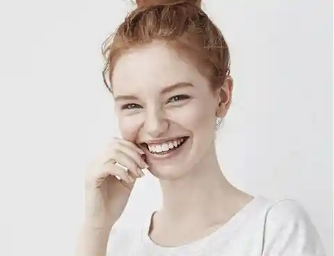 Redheaded girl smiling with a white shirt.