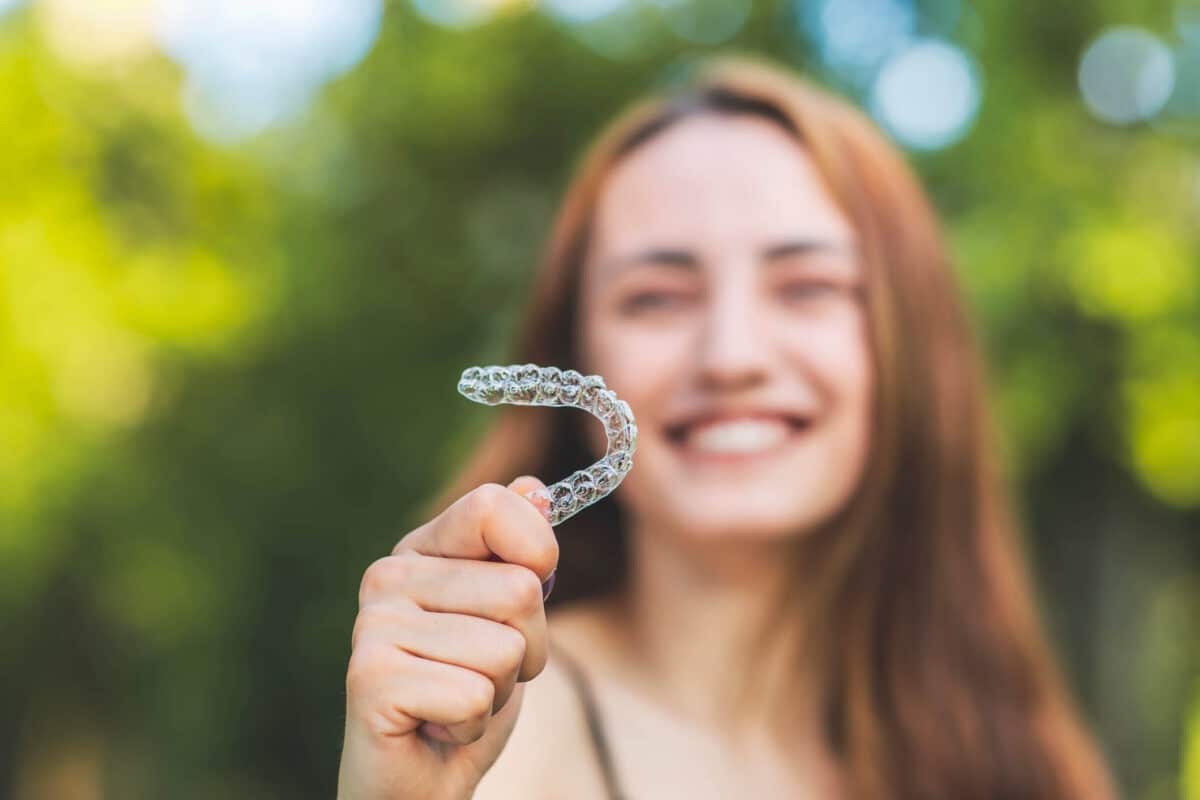 a blurred out person holding invisalign clear aligners in focus