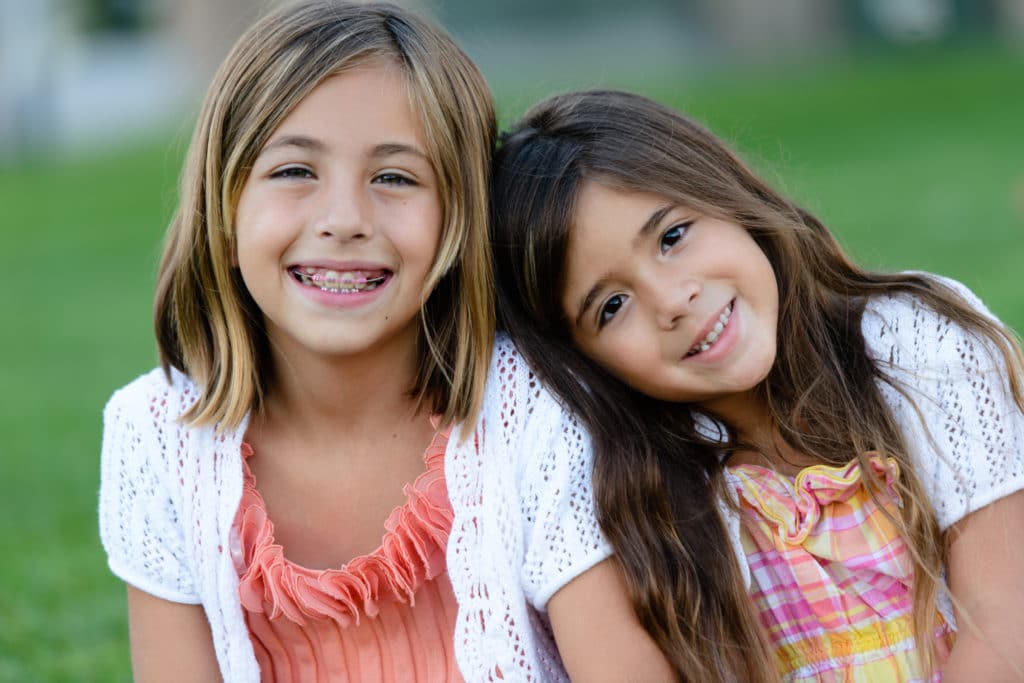 a portrait of two children with braces smiling at the camera