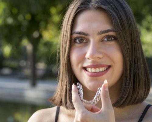 Beautiful smiling Turkish woman is holding an invisalign bracer Beautiful smiling Turkish woman is holding an invisalign bracer