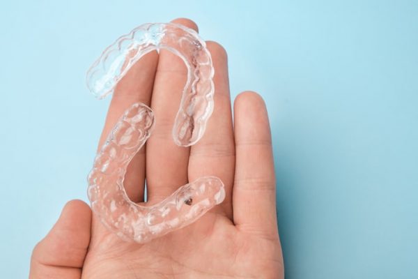 two clear aligners on the palm of a hand